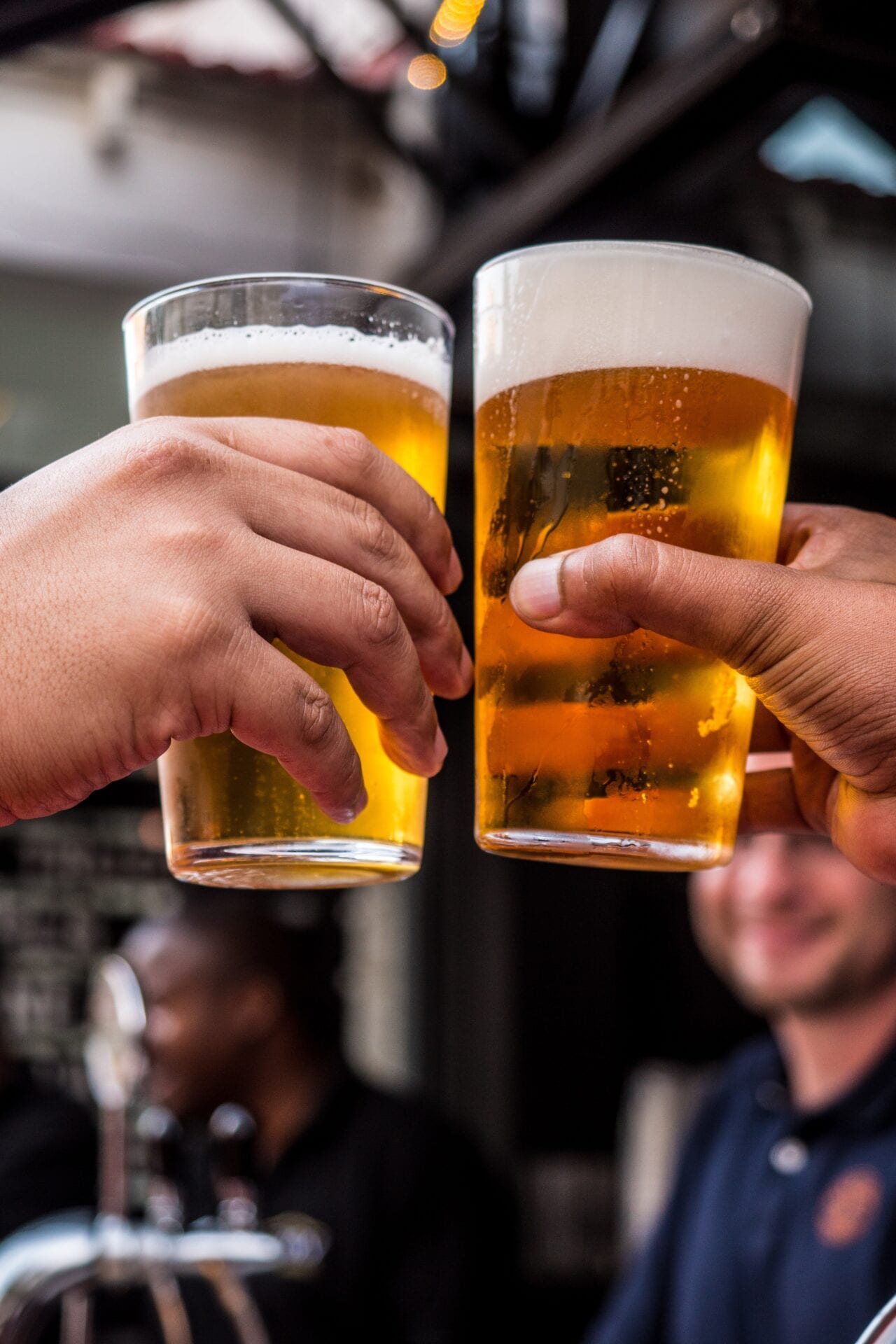 Two people holding up their glasses of beer.